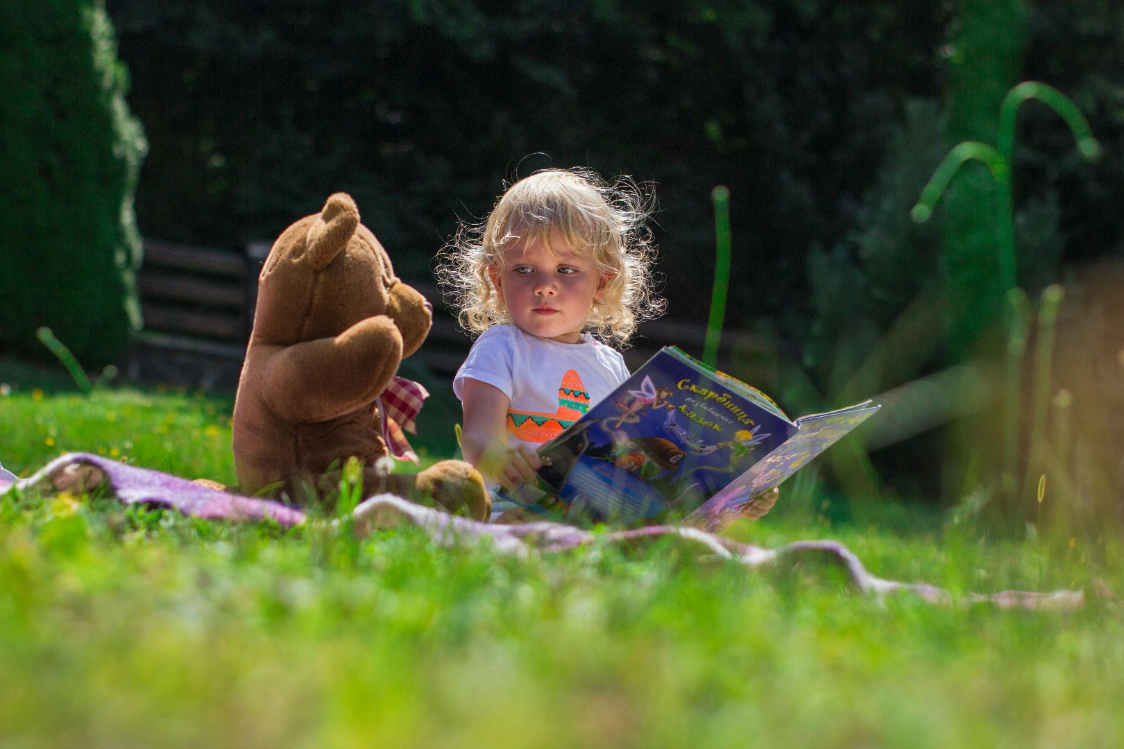 Child in garden with bear and book - photo by Andy Kuzma